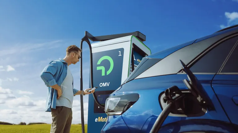 мъж зарежда на елекрическа зарядна станция omv