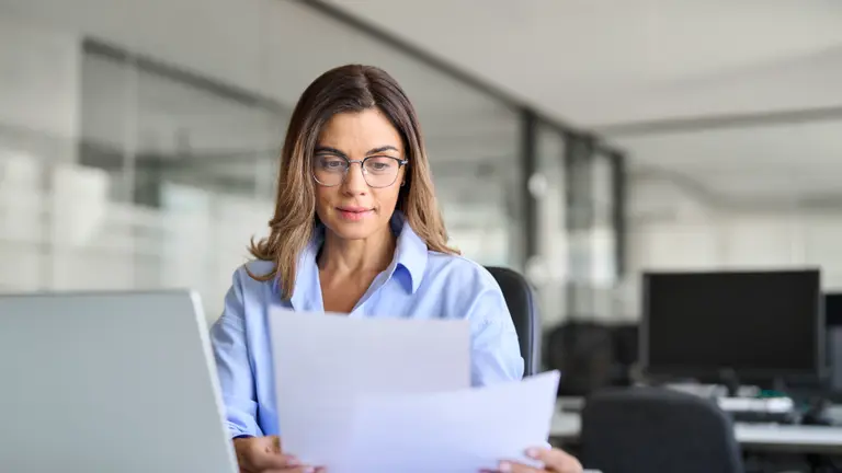 Busy mature business woman entrepreneur working in office and checking legal documents.