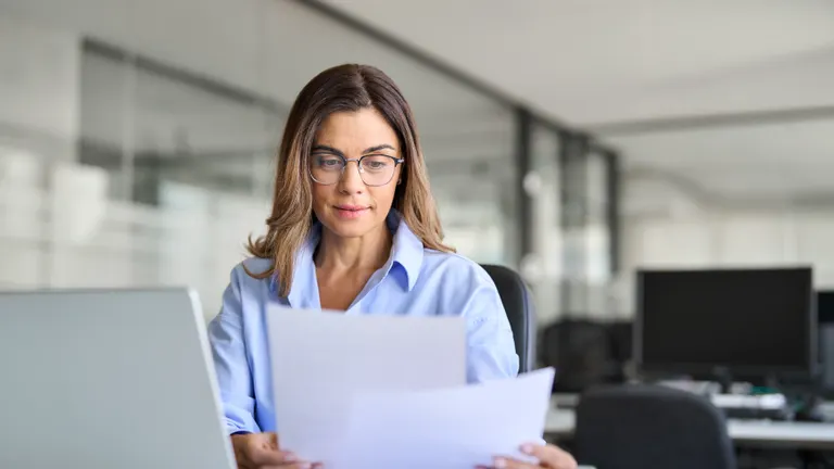 Busy mature business woman entrepreneur working in office and checking legal documents.